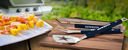 Barbecue tools with skewers on a plate near a grill.